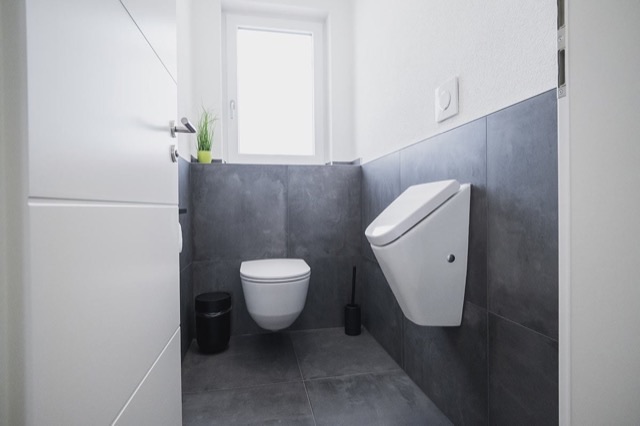 Gäste-WC mit grauen Fliesen, Urinal und wandhängendem WC